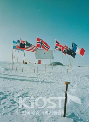 남극점에 설치된 극점표식과 남극조약 원초 서명국 12개국의 국기 의 사진
